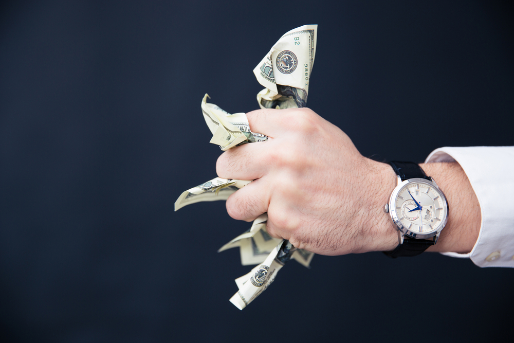 Closeup image of a businessman hand holding bills of US dollar in fist